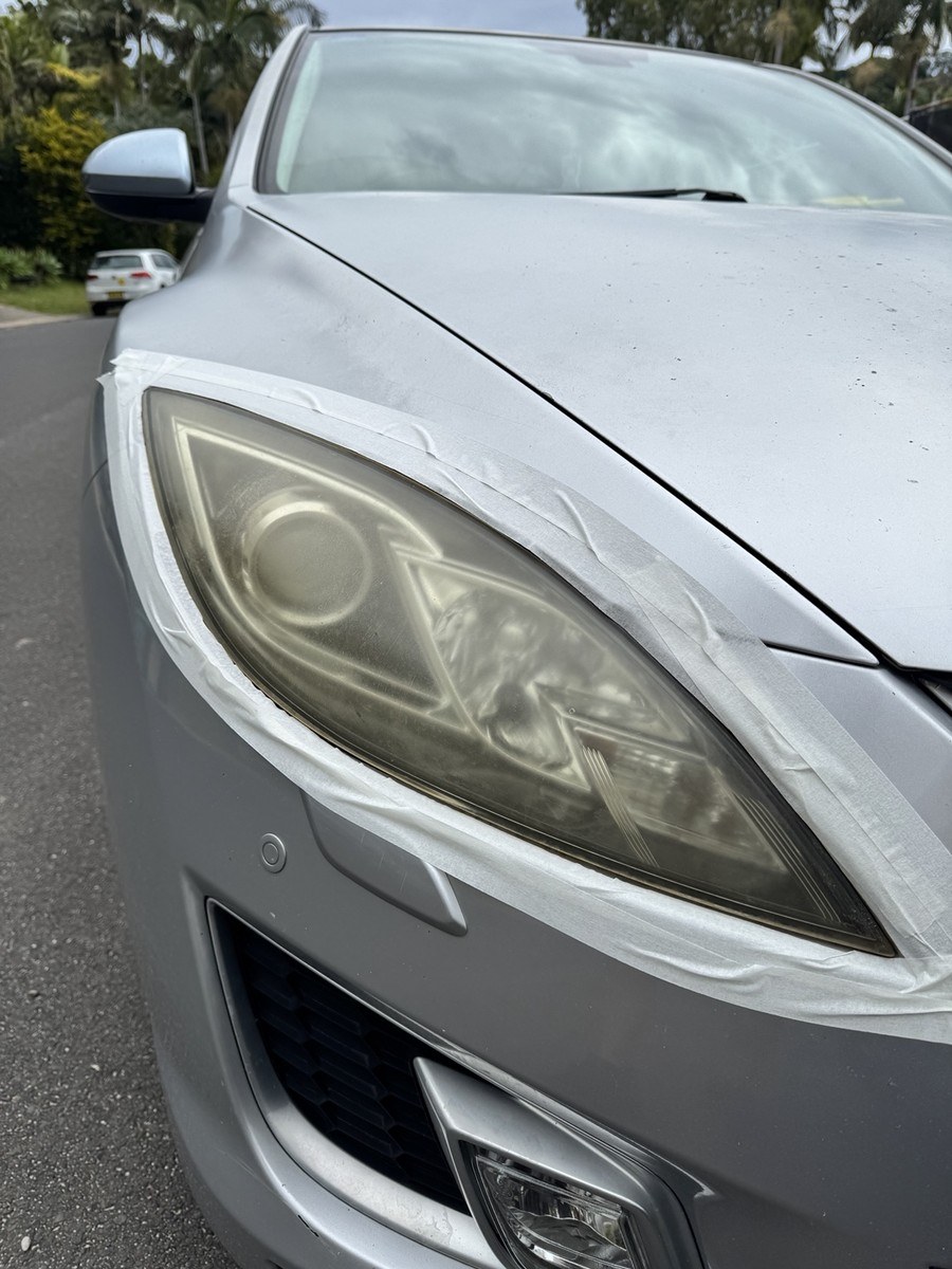 Sedan headlight before restoration, hazy with visible oxidation
